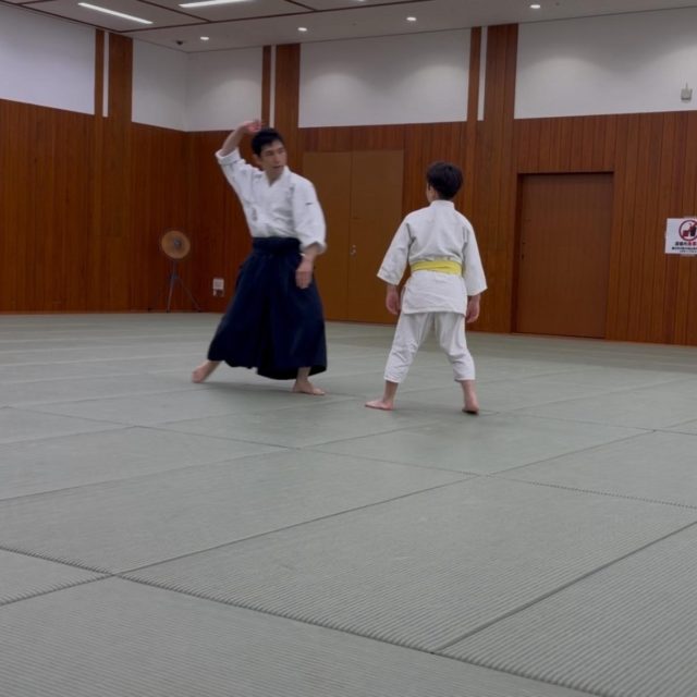 少年部では横面打ち四方投げの稽古を行いました。  相手の横面打ちに対し、前足を引いて間合いをとりながら攻撃をかわし、その動きと同時に相手の手刀を捉えて四方投げへとつなげます。  このかわし方は、頭の位置を後方へ移動させるため、ジャブやストレート、フックなどをバックステップでかわす動きにも通じる要素があります。  護身術において、相手の攻撃をかわすことは、大きな怪我を防ぐだけでなく、安全にその場から離れるための隙をつくるという意味でも非常に重要です。  合気道の稽古は、単に型を反復するだけではありません。「この動きでどのような攻撃を避けられるのか」「なぜこの動きをするのか」を考えながら稽古することで、護身術としての実践力も高まります。  少年部でも、一つひとつの技の意味を理解しながら、楽しく真剣に稽古に取り組んでいます！  #合気道 #少年部 #護身術 #四方投げ #武道 #習い事 #港区 #港区スポーツセンター #親子習い事 #子どもの習い事 #田町 #宇宙の会